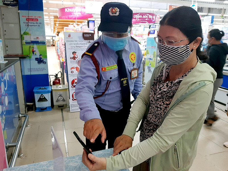 Bảo vệ Siêu thị Co.opmart Trà Vinh hướng dẫn người dân quét mã QR. Trà Vinh tăng cường khai báo y tế điện tử trong phòng, chống Covid-19 -0