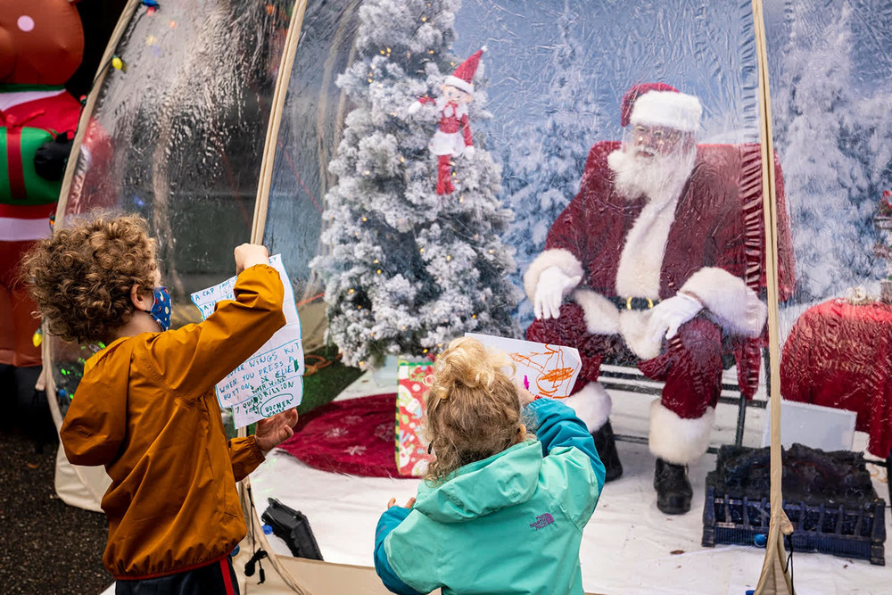 Ông già Noel ngồi trong quả cầu tuyết "giãn cách xã hội" tại TP Seattle, Mỹ, và đọc thư của hai em nhỏ. (Ảnh: Getty Images) 1 -0