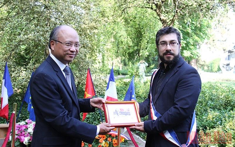 Đại sứ Đinh Toàn Thắng trao tặng Phó Thị trưởng Florian Vigneron bức tranh tem Chủ tịch Hồ Chí Minh do Bưu điện Pháp phát hành nhân dịp kỷ niệm 100 năm Người đặt chân đến Pháp. Kỷ niệm Ngày sinh Chủ tịch Hồ Chí Minh tại Pháp -0