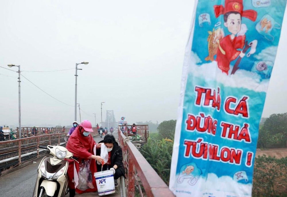 Các nhóm tình nguyện hỗ trợ người dân thả cá tại khu vực cầu Long Biên. Người dân Hà Nội thả cá chép tiễn ông Táo về trời -0
