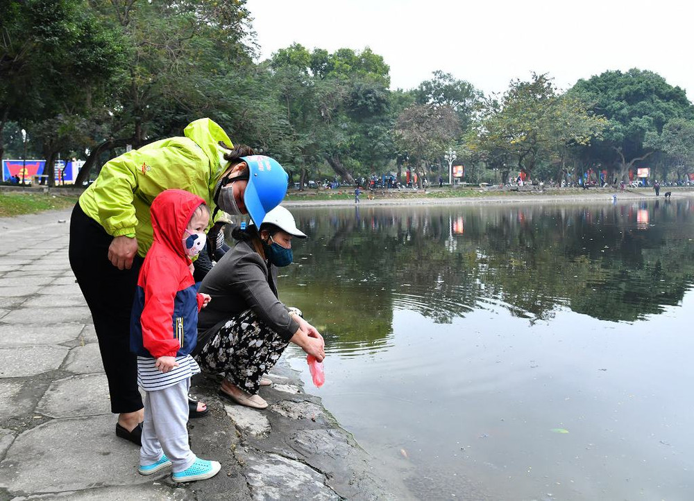 Nhiều trẻ nhỏ hào hứng theo cha mẹ đi thả cá vàng ngày Tết và được nhắc nhở mang túi nilon về sau khi thả cá vàng. Trước diễn biến phức tạp của dịch Covid-19, đa phần mọi người đều chấp hành nghiêm việc đeo khẩu trang. Người dân Hà Nội thả cá chép tiễn ông Táo về trời -0