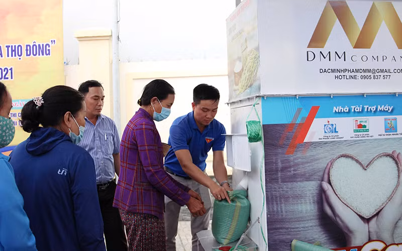 Lê Thanh Hải (ngoài cùng bên phải) hỗ trợ người dân nhận gạo tại cây ATM.