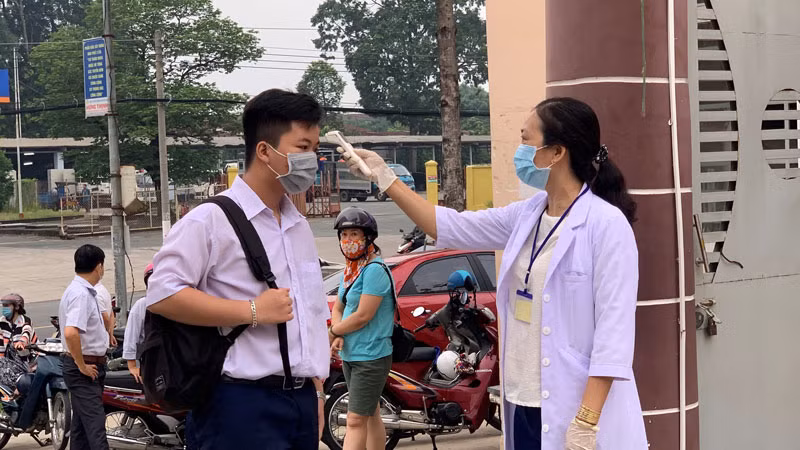 Cán bộ y tế đo thân nhiệt cho thí sinh tại Hội đồng thi Trường THCS Nguyễn Thị Minh Khai, TP Thủ Dầu Một.