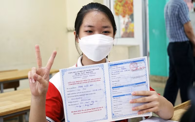 Trẻ được tiêm và nhận chứng nhận tiêm vắc-xin phòng Covid-19.