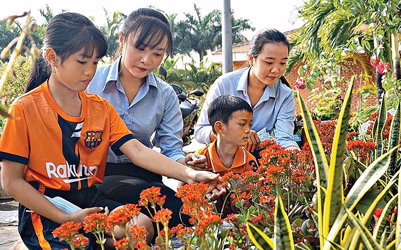 Sinh viên Trường cao đẳng Cộng đồng Cà Mau hướng dẫn các em nhỏ Làng trẻ em SOS (phường 5, TP Cà Mau, tỉnh Cà Mau) chăm sóc hoa trong vườn. Ảnh: YẾN NHI