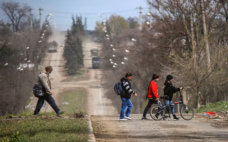 Người dân đi qua một tuyến đường tại thành phố cảng Mariupol, Ukraine, ngày 21/4. (Ảnh: Reuters)