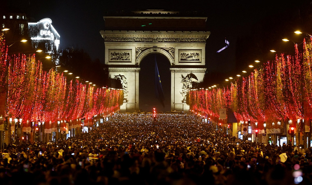 Người dân Paris tập trung tại đại lộ Champs-Élysées đón năm mới 2022, dù màn trình diễn ánh sáng và pháo hoa truyền thống đã bị hủy. (Ảnh: Reuters) Thế giới chào năm mới 2022 trong bối cảnh thắt chặt quy định phòng, chống dịch Covid-19 -0
