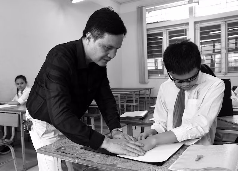 Thầy Ngô Văn Hiếu cần mẫn hướng dẫn, chỉ bảo các em học sinh từng chữ với kinh nghiệm của một người đi trước có chung hoàn cảnh với các em.