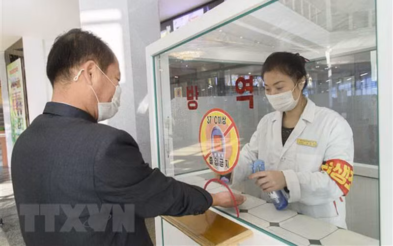 Khử khuẩn tay, đo thân nhiệt, nhằm ngăn chặn sự lây lan của dịch Covid-19 trước khi vào trung tâm thương mại ở Bình Nhưỡng, Triều Tiên. (Ảnh: AFP/TTXVN)
