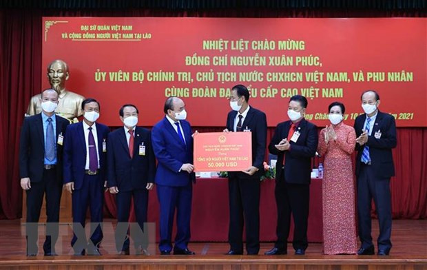 Chủ tịch nước Nguyễn Xuân Phúc trao số tiền ủng hộ cộng đồng người Việt Nam tại Lào khắc phục khó khăn do dịch Covid-19 gây ra. (Ảnh: TTXVN) Chủ tịch nước kết thúc tốt đẹp chuyến thăm hữu nghị chính thức Lào -0