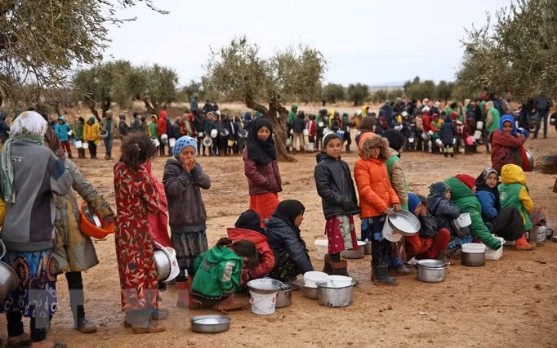 Người dân xếp hàng chờ được phát lương thực cứu trợ tại trại tị nạn ở Yazi Bagh, Aleppo, Syria. (Ảnh: AFP/TTXVN)