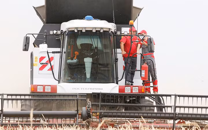 Người dân Nga vận hành máy gặt đập liên hợp. Ảnh: TASS
