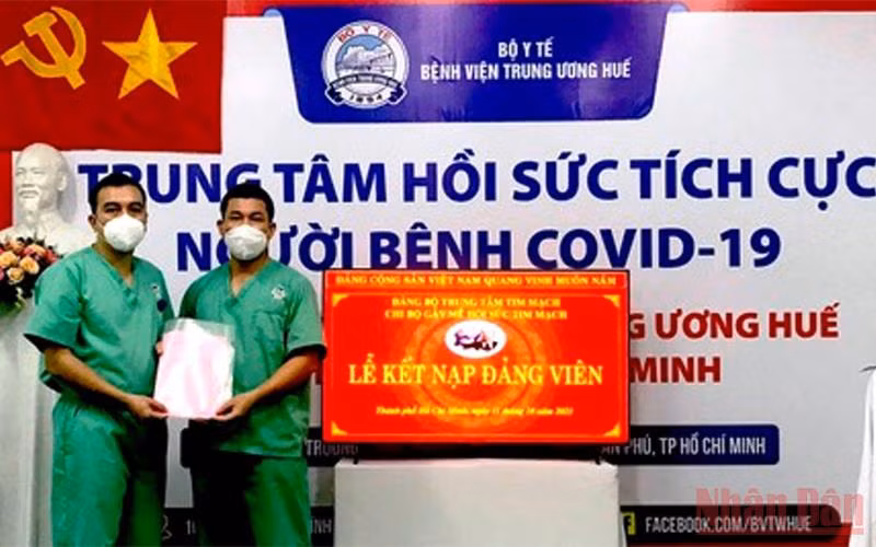 Điều dưỡng Nguyễn Thành Trung (bên trái) vinh dự được đứng vào hàng ngũ của Đảng.