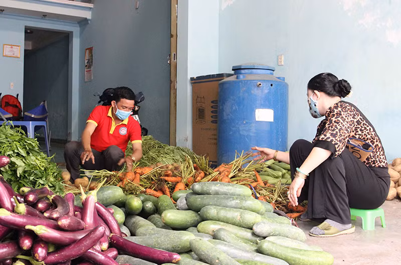 Anh Nguyễn Ngọc Bình (áo đỏ) chuẩn bị rau củ hỗ trợ người dân.