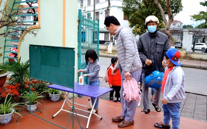 Học sinh Trường mầm non Hoa Đào thực hiện sát khuẩn tay và đeo khẩu trang trước khi vào lớp học.
