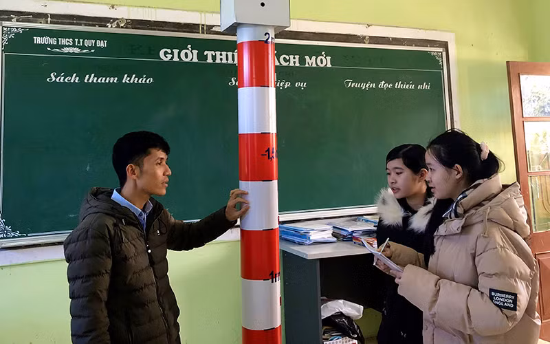Hai học sinh Trang và Như trao đổi với thầy giáo Cao Ngọc Giang về thiết bị cảnh báo mực nước thông minh.