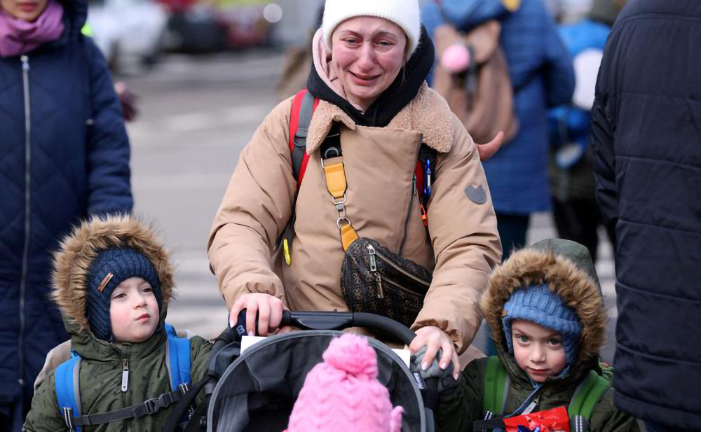 Người phụ nữ không kìm được nước mắt khi cùng các con rời Ukraine tới Romania. (Ảnh: Reuters) Bảy ngày chiến sự tại Ukraine -0