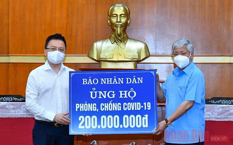Tổng Biên tập Báo Nhân Dân Lê Quốc Minh trao số tiền ủng hộ phòng, chống dịch Covid-19 cho Chủ tịch Ủy ban TƯ MTTQ Việt Nam Đỗ Văn Chiến. Ảnh: Duy Linh