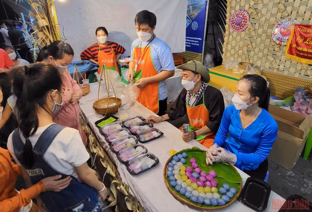 Khách tham quan thích thú thưởng thức bánh dân gian tại lễ hội.