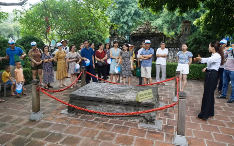 Khách du lịch tham quan “Long sàng” trước nghi môn ngoại đền vua Đinh.