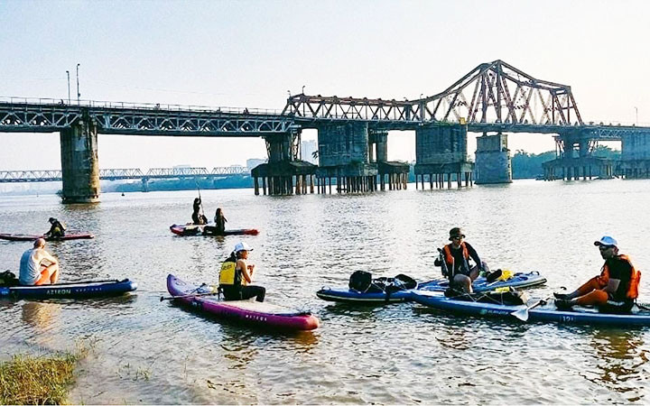 Khách du lịch tham gia tua du lịch chèo SUP trên sông Hồng.