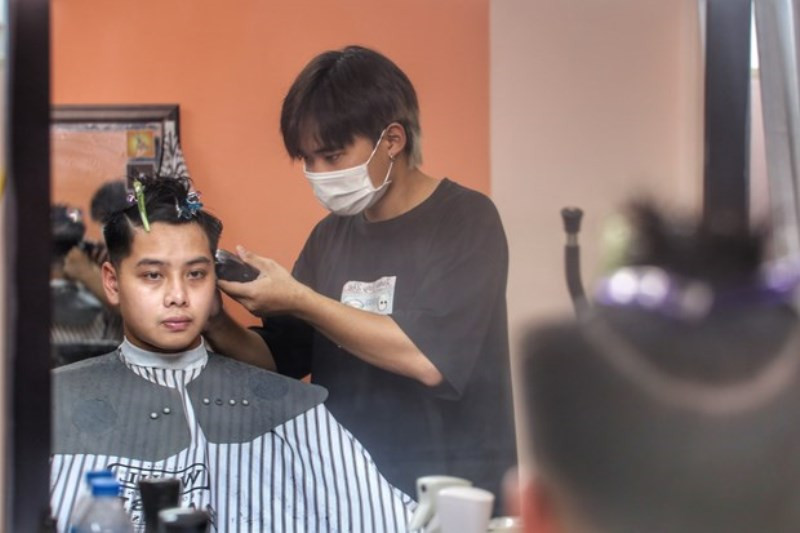 Các cửa hàng cắt tóc mỗi lượt chỉ nhận từ một đến hai khách, bảo đảm giãn cách phòng dịch; thợ cắt tóc bắt buộc đeo khẩu trang khi phục vụ khách. Hà Nội: Dịch vụ cắt tóc, gội đầu hút khách ngày đầu mở cửa lại -0