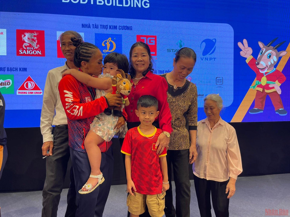 Lực sĩ Bùi Thị Thoa hạnh phúc bên người thân. Đằng sau tấm huy chương: Những hậu phương vững chắc -0