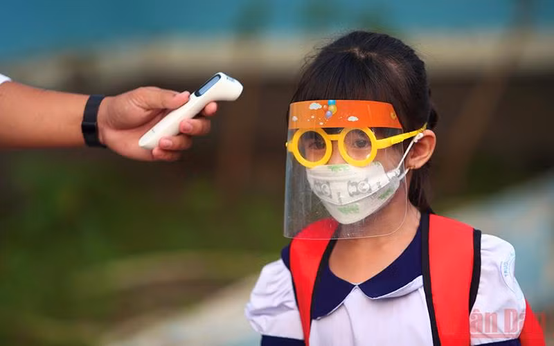 Đo thân nhiệt cho học sinh trước khi vào Trường tiểu học Thạnh An, huyện Cần Giờ, TP Hồ Chí Minh. (Ảnh: HẢI LONG)