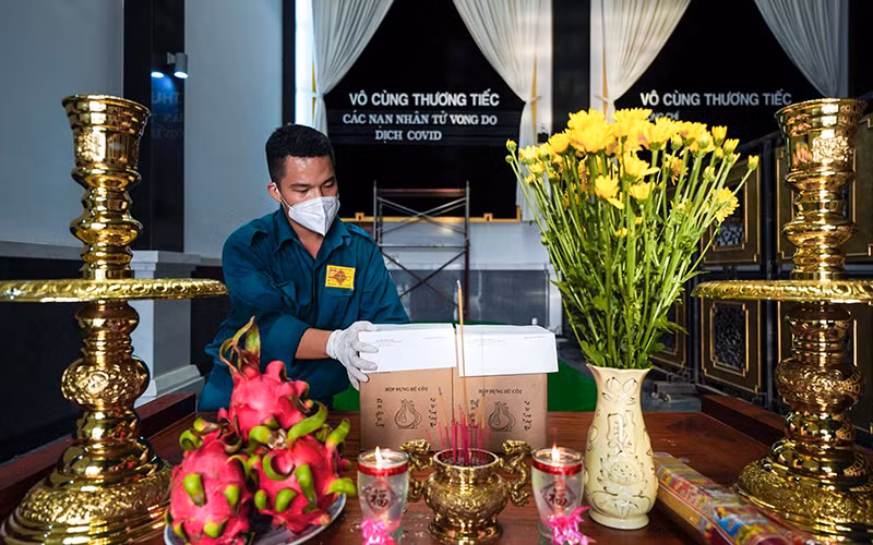 Một chiến sĩ dân quân tự vệ thắp hương cho một nạn nhân tử vong trong dịch Covid-19. Ảnh: Hoàng Triều.