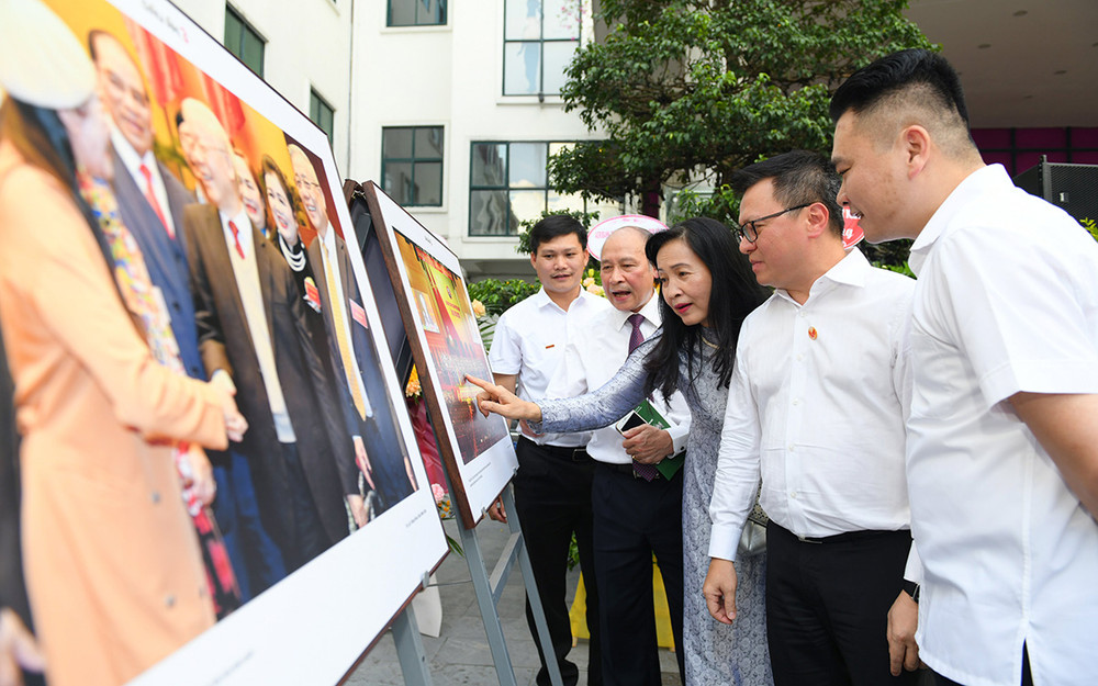 Ông Lê Quốc Minh nghe giới thiệu về các tác phẩm trưng bày trong triển lãm. Ảnh: THÀNH ĐẠT Những bức ảnh kể chuyện -0