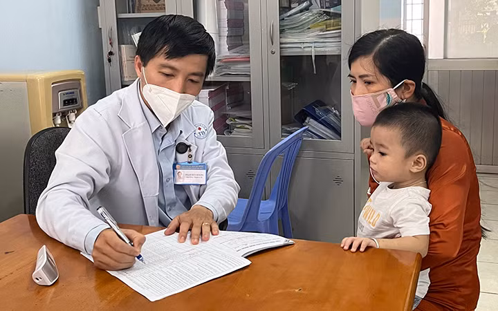 Bác sĩ Phạm Huy Hoàng, Trưởng trạm Y tế phường Trường Thọ, thành phố Thủ Đức, TP Hồ Chí Minh, khám bệnh cho trẻ. (Ảnh: Mạnh Hảo)
