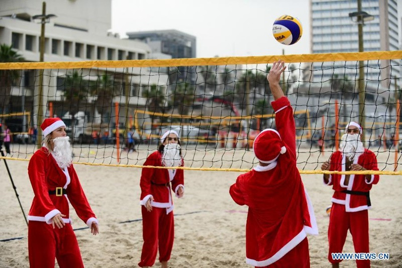 Người dân tại TP Tel Aviv, Israel chơi bóng chuyền trong trang phục của ông già tuyết. (Ảnh: Tân Hoa xã) 1 -0