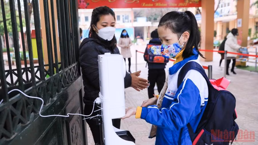 Các giáo viên trường tiểu học tại huyện Hoài Đức nhắc các em học sinh sát khuẩn tay, kiểm tra thân nhiệt trước khi vào học. (Ảnh: DUY LINH)
