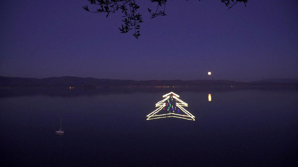 Cây thông Noel khổng lồ được thắp sáng trên mặt hồ Trasimeno ở Castiglione del Lago, Italia. (Ảnh: Reuters) Châu Âu đón Giáng sinh trong lo ngại làn sóng Omicron -0