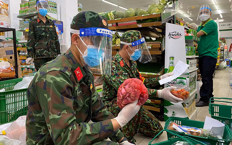 Các chiến sĩ chọn hàng theo đơn tại cửa hàng theo yêu cầu mua hộ của người dân phường 2, quận 5, TP Hồ Chí Minh. (Ảnh: Quý Hiền)