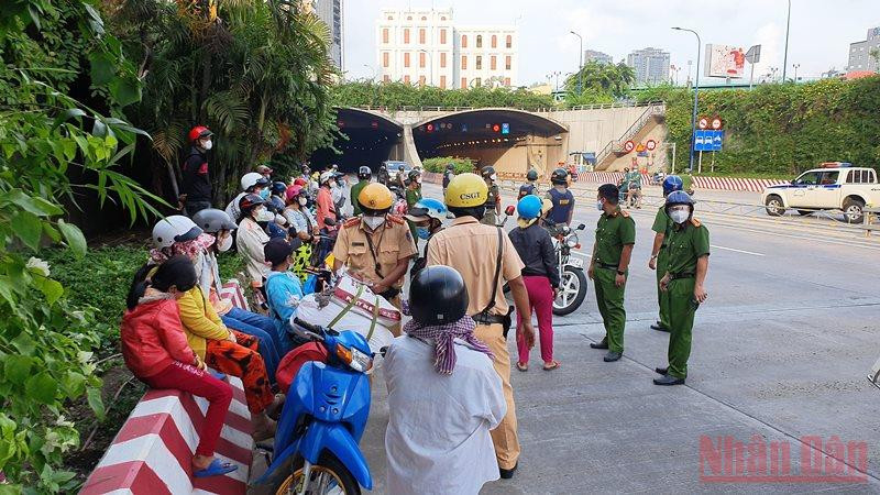 Các cơ quan chức năng tuyên truyền, vận động người dân quay về nơi ở khi đang trên đường về quê bằng xe máy tại khu vực hầm Thủ Thiêm, TP Thủ Đức. (Ảnh: QUANG QUÝ)