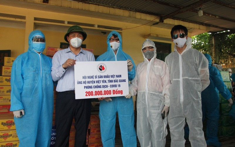 Chủ tịch UBND huyện Việt Yên Nguyễn Văn Phương (người đội mũ cối) nhận biển biểu trưng ủng hộ 200 triệu đồng cho huyện Việt Yên từ NSND Thúy Mùi, NSND Thúy Hường, NSƯT Xuân Bắc. 4-1622365037714.jpg
