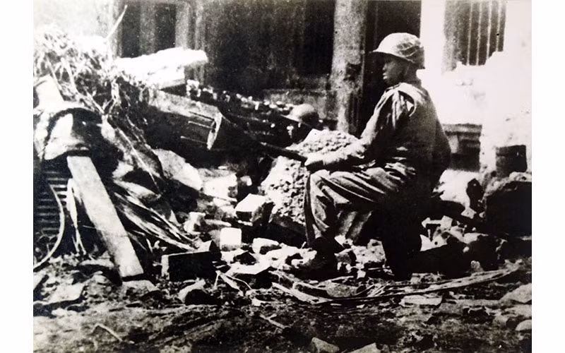 Chiến sĩ Trần Thành, đoàn viên Thanh niên cứu quốc Hoàng Diệu, ôm bom ba càng, sẵn sàng tiêu diệt xe tăng địch trên đường phố Thủ đô Hà Nội ngày 23-12-1946 - những ngày đầu Toàn quốc kháng chiến, với ý chí "Quyết tử cho Tổ quốc quyết sinh". Ảnh: Nguyễn Bá Khoản (TTXVN)