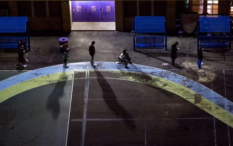 Cử tri xếp hàng tại sân chơi của một trường tiểu học tại bang New York từ sáng sớm để chờ điểm bỏ phiếu mở cửa. (Ảnh: AP)