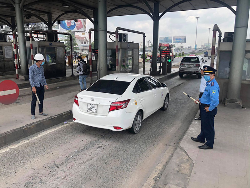 Lực lượng chức năng hướng dẫn xe qua trạm sau khi tạm dừng thu phí.