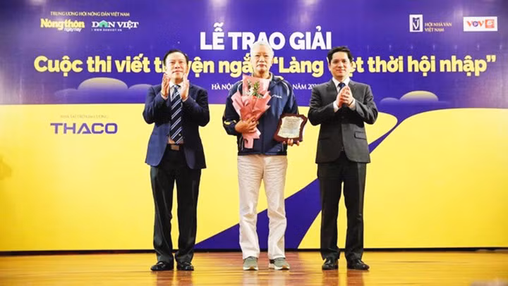 Đại diện Ban tổ chức Cuộc thi trao giải nhất cho nhà văn Trần Chiến, tác giả truyện ngắn Con chú con bác. Ảnh: NGÔ HÀ