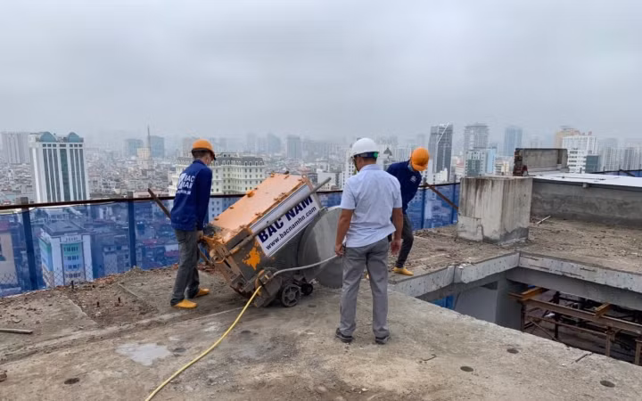 Công nhân Công ty Đầu tư xây dựng Bắc Nam tiến hành cắt sàn bê-tông mái tầng 18 công trình sai phạm số 8B phố Lê Trực.