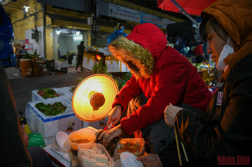 Vào ban đêm người lao động tại khu vực chợ Long Biên vừa ăn cơm vừa mang lò sưởi ra bán hàng. (Ảnh: THÀNH ĐẠT) Hà Nội: Người lao động và người vô gia cư căng mình chống chọi với giá rét -0