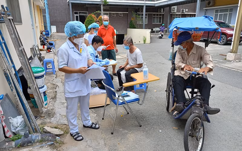 Nhân viên y tế kiểm tra kỹ thông tin trước bên ngoài phòng tiêm chủng.
