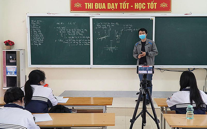 Giáo viên Trường THPT Huỳnh Thúc Kháng (tỉnh Nghệ An) vừa dạy trực tiếp ở lớp vừa phát online cho học sinh đang phải cách ly ở nhà. (Ảnh: MỸ HÀ) Triển khai nhiệm vụ năm học linh hoạt -0