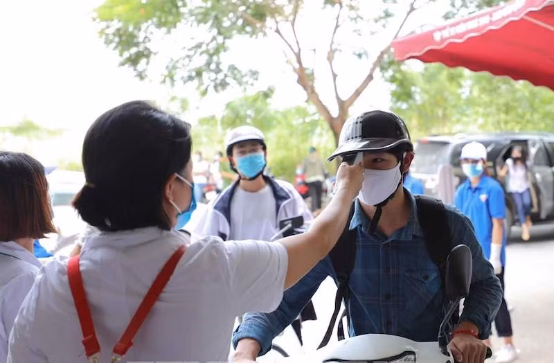 Cán bộ y tế kiêm tra thân nhiệt của thí sinh tham dự Kỳ thi tốt nghiệp THPT 2020 tại Điểm thi Trường THCS Nam Từ Liêm (Cầu Giấy, Hà Nội) chiều 8-8 (Ảnh: THANH TÙNG)