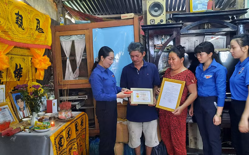 Quyền Bí thư Tỉnh đoàn Vĩnh Long Nguyễn Thụy Yến Phương trao Huy hiệu “Tuổi trẻ dũng cảm” cho gia đình em Nguyễn Minh Quân.