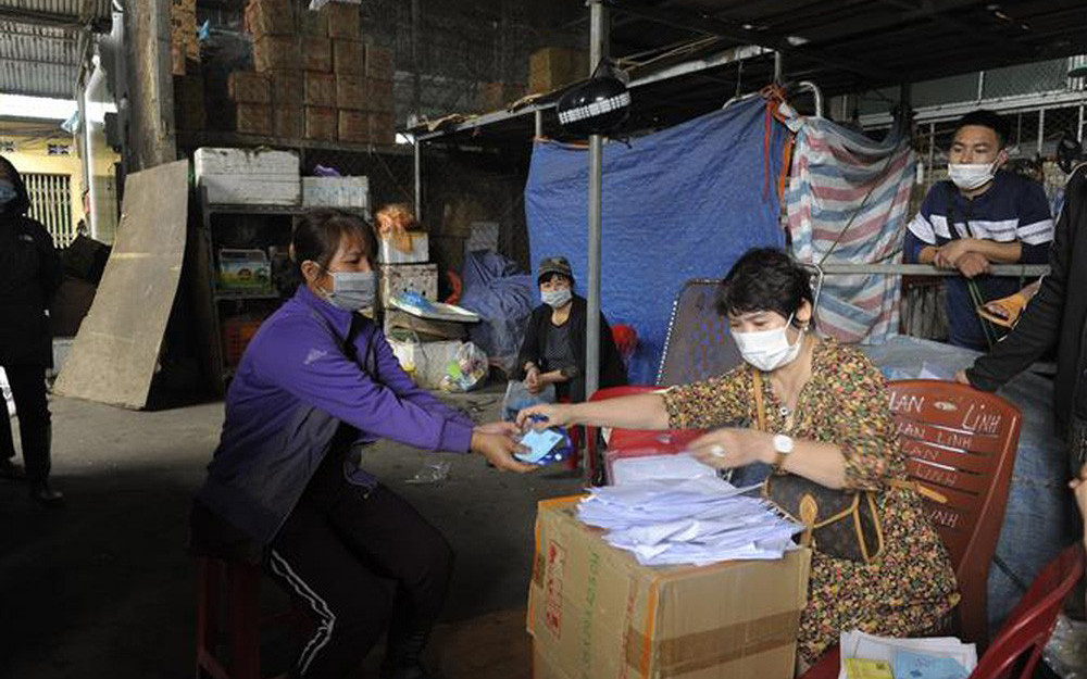 Ban Quản lý chợ Long Biên phát thẻ ra vào cho các hộ kinh doanh. (Ảnh: Mạnh Khánh-TTXVN) Chợ Long Biên hoạt động trở lại từ 0 giờ ngày 21/10 -1