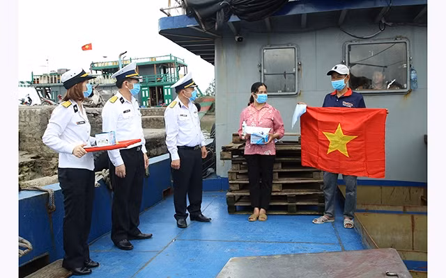 Đại diện Bộ Tư lệnh Vùng 1 (Quân chủng Hải quân) trao vật tư y tế và cờ Tổ quốc tặng ngư dân tại cảng cá Mắt Rồng (huyện Thủy Nguyên).