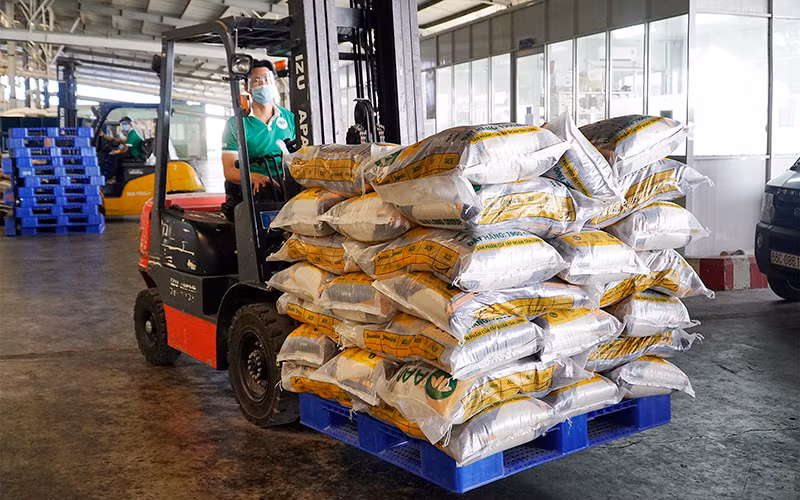 Bốc dỡ gạo ở chi nhánh Công ty cổ phần Tập đoàn Tân Long tại Đồng Tháp. (Ảnh NGỌC TÀI)